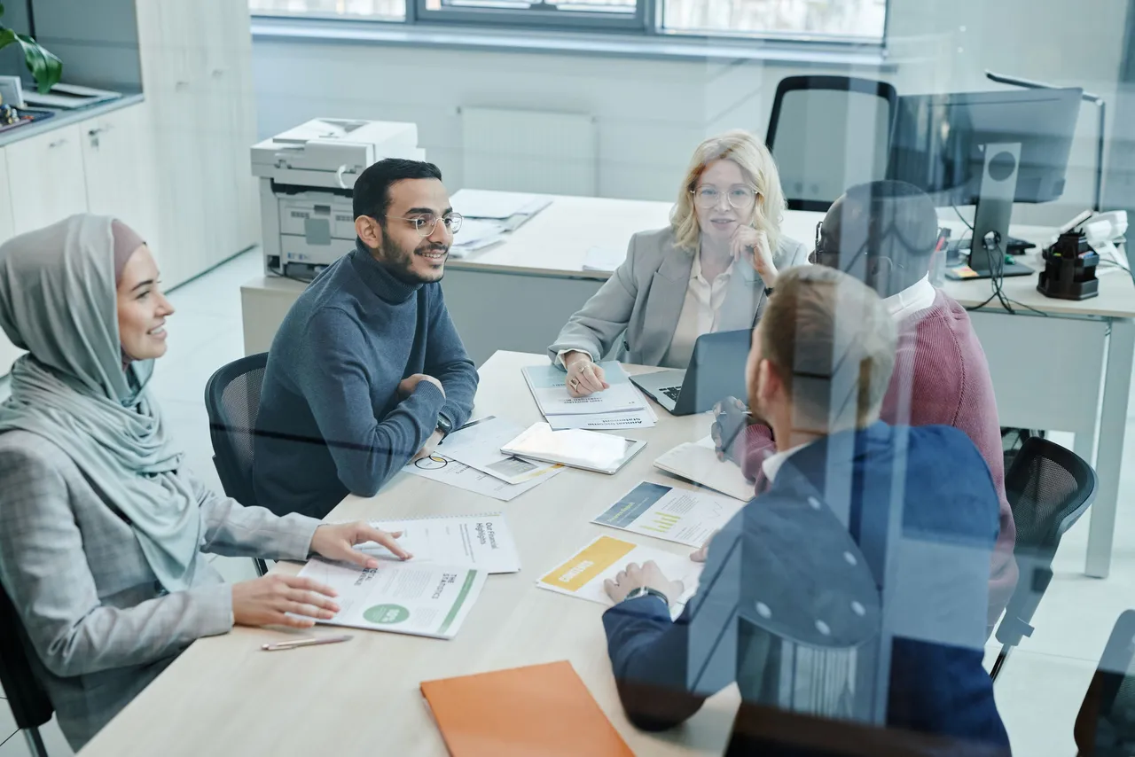 Equipe diversa reunida em uma sala de reunião de escritório moderno durante uma conversa de trabalho.