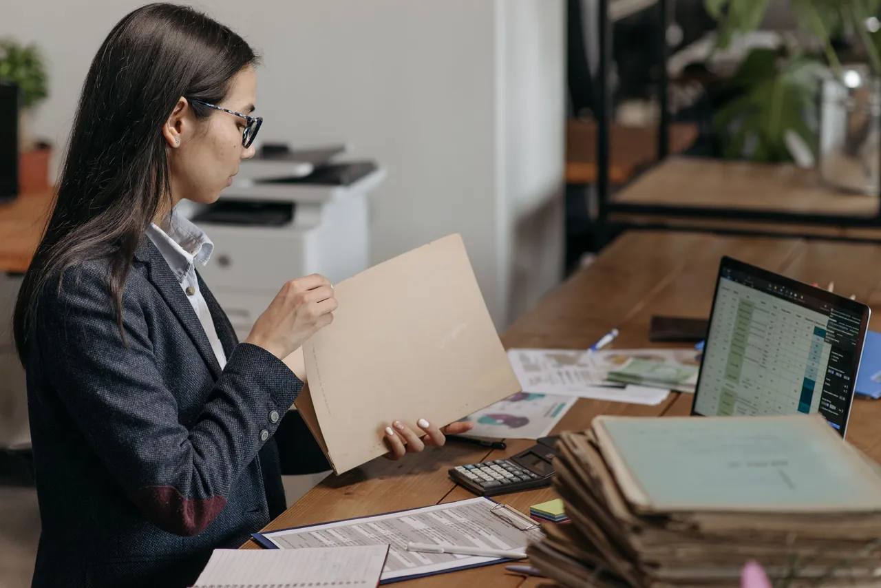 Gestora de RH analisando documentos de enquadramento da empresa sobre uma mesa de escritório.